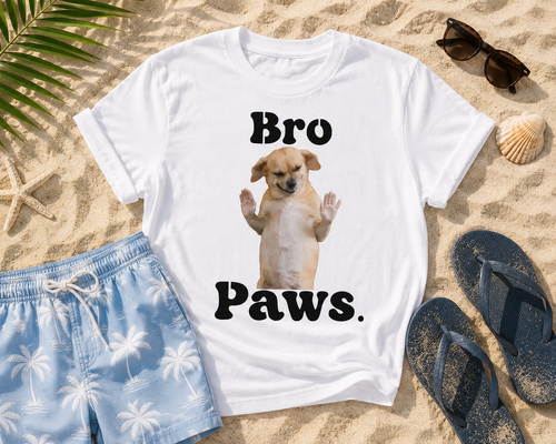 White t-shirt with a dog graphic and 'Bro Paws' text on sand with shorts and flip-flops.